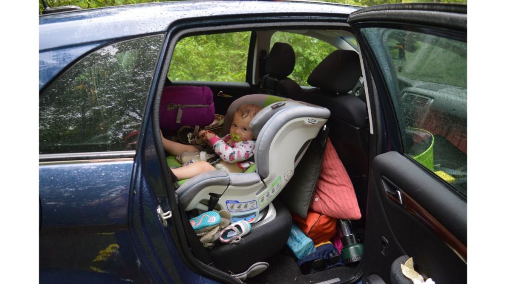 Child in car surrounded with camping gear