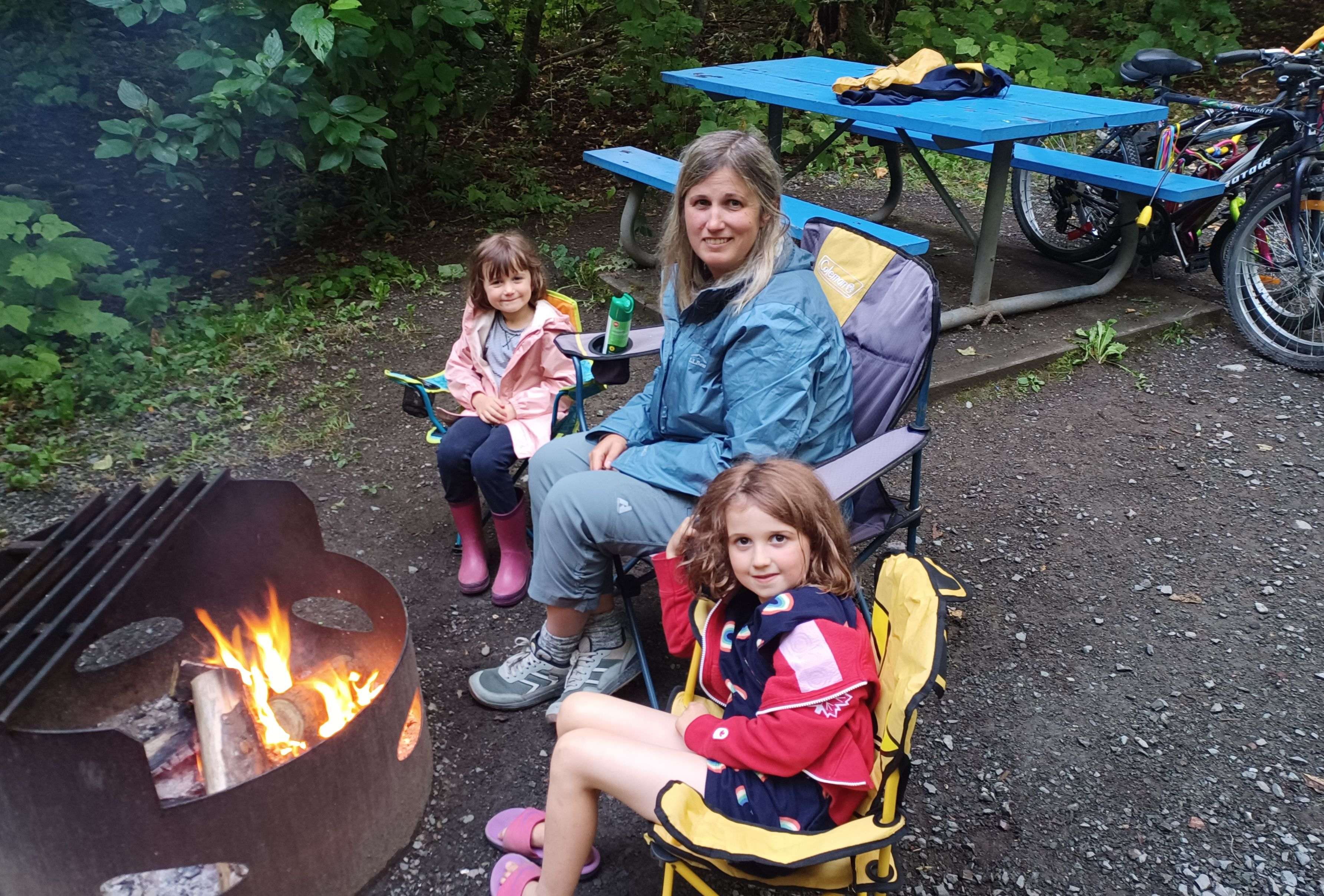 Family smiling around campfire in rain