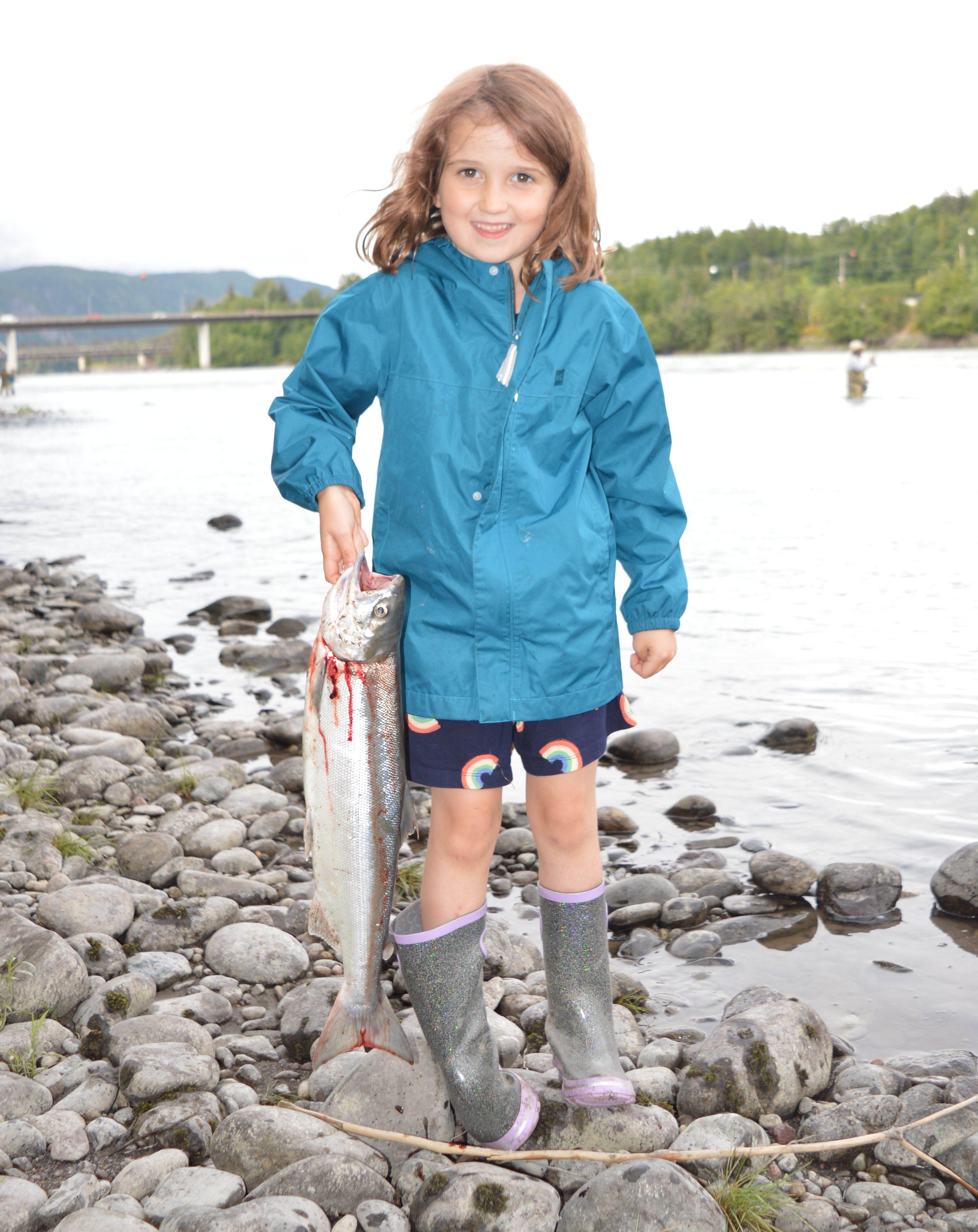 Child holding salmon on riverfront