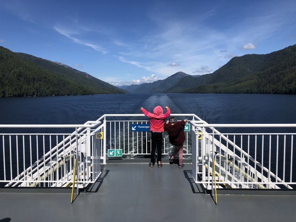 Girls on back of ferry boat with mountains