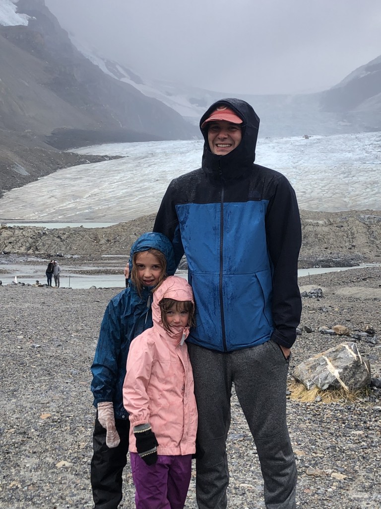 Family standing at Athabasca Glacier in rain gear