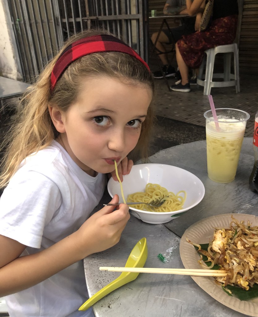 Child eating noodles at a street stand