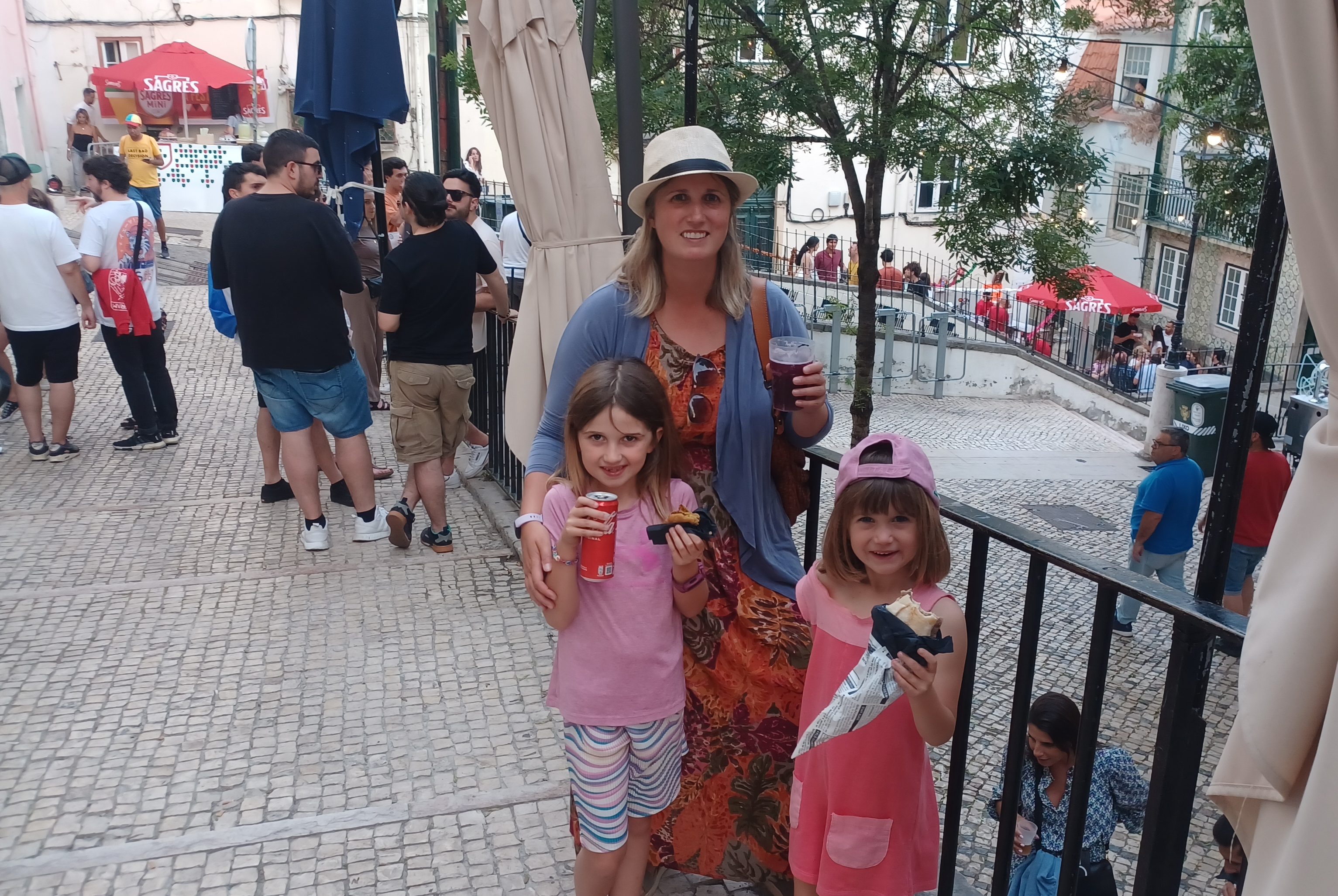 Two girls and woman enjoying snacks at a street festival in Lisbon