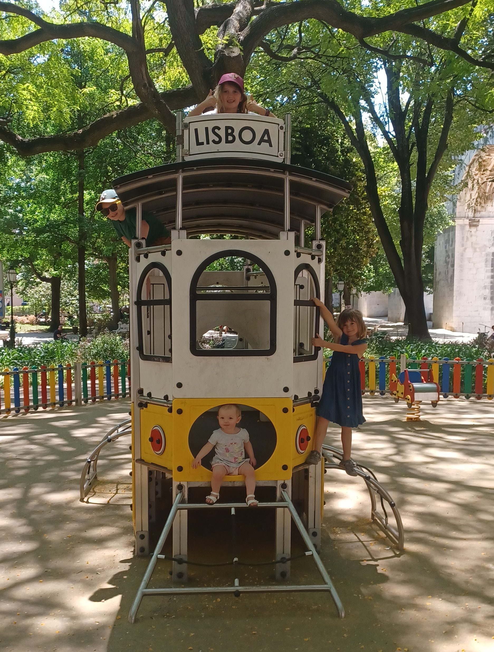 Four childen on a playground slide in shape of a tram