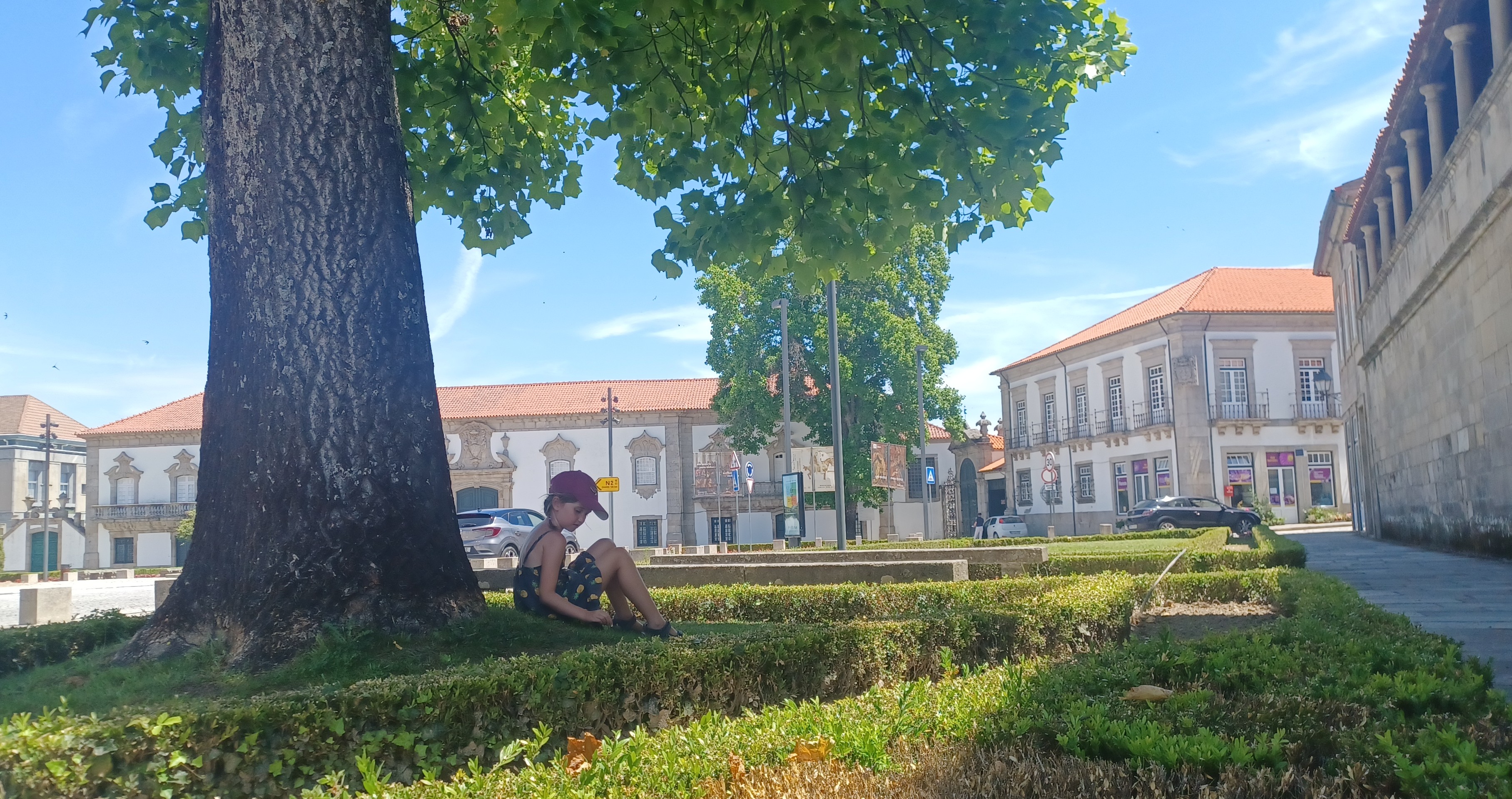 Child under tree in Portugese town centre