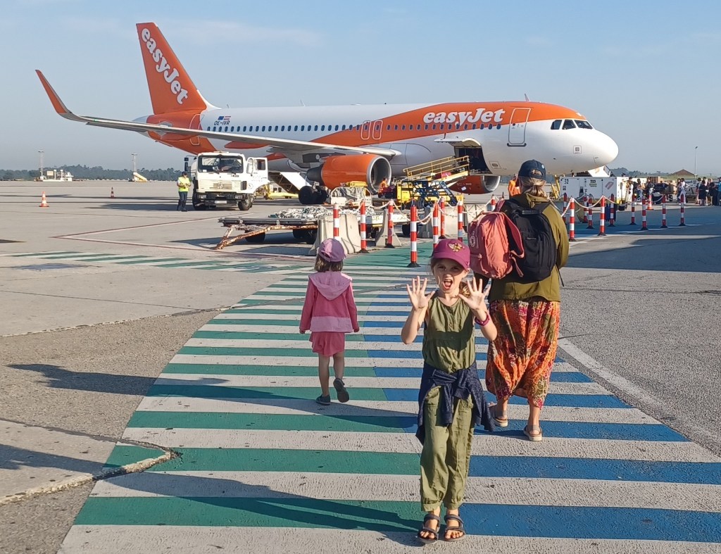 Child smiling in front of easy jet plane on tarmac